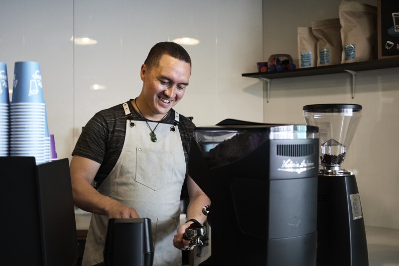 Illustrative image: Young man working a coffee machine